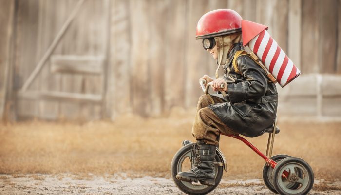 Boy in the image of a rider and a rocketman play in the backyard of the house
